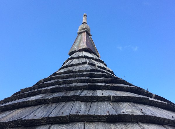Détail 1 — flèche et faîteau du toit sur ciel bleu